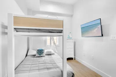 a bedroom with a bunk bed and a tv at The Village Happy Life Condo - Private Beach Access Pool & Hot Tub in Rosemary Beach