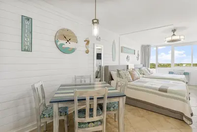 a bedroom with a bed and a table and chairs at Beach Front Ocean View Condo - Top of the Gulf 804 in Panama City Beach