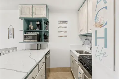 a kitchen with white cabinets and a refrigerator at Beach Front Ocean View Condo - Top of the Gulf 804 in Panama City Beach