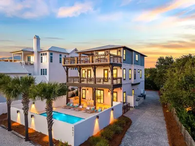 a large house with a swimming pool in front of it at Four Blue Palms by 30A Escapes in Seacrest