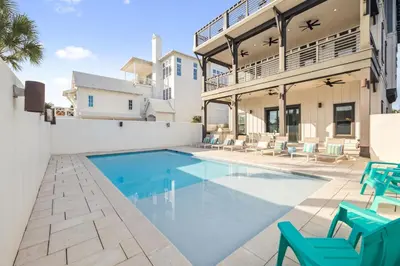a swimming pool in the backyard of a house with blue chairs at Four Blue Palms by 30A Escapes in Seacrest