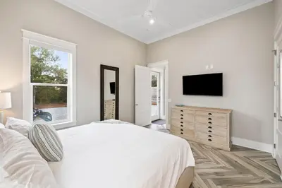 a white bedroom with a bed and a television at Four Blue Palms by 30A Escapes in Seacrest