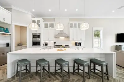 a kitchen with a large white island with four stools at Four Blue Palms by 30A Escapes in Seacrest