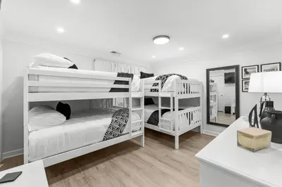 a white room with two bunk beds and a desk at Gulf Highlands #177 by Nautical Properties in Panama City Beach