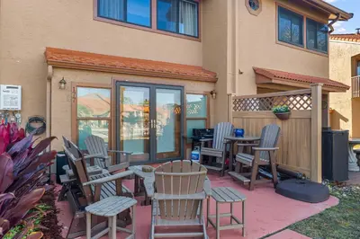 a patio with chairs and tables in front of a building at Gulf Highlands #177 by Nautical Properties in Panama City Beach