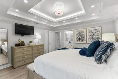 a bedroom with a large white bed and a flat screen tv at Gulf Highlands #177 by Nautical Properties in Panama City Beach