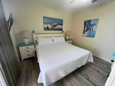 a bedroom with a bed with a white bedspread and a table at Ocean Front Studio with Epic Gulf Views in Panama City Beach