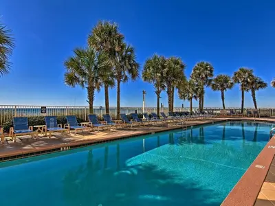 a swimming pool with chairs and palm trees at Ocean Front Studio with Epic Gulf Views in Panama City Beach
