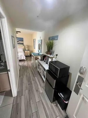 a living room with wood floors and a room with a bed at Ocean Front Studio with Epic Gulf Views in Panama City Beach