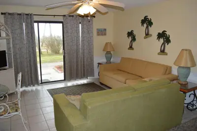 a living room with a couch and a sliding glass door at The Summit Condominiums in Panama City Beach