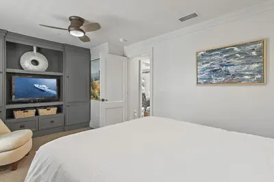 a white bedroom with a bed and a tv at WaterHouse 202 in Inlet Beach