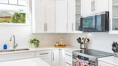 a white kitchen with white cabinets and a sink at Modern 5BDR w Private Pool 2 min Walk to the Beach Montoute by AvantStay in Panama City Beach