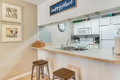 a kitchen with a sink and a counter with two stools at Walk to Beach PCB Gem with Community Pool Access! in Panama City Beach