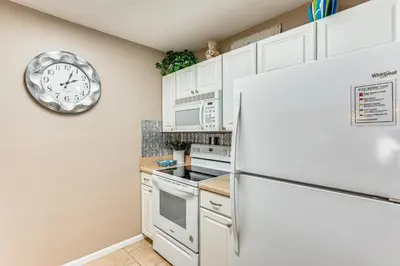 a kitchen with a refrigerator and a clock on the wall at Walk to Beach PCB Gem with Community Pool Access! in Panama City Beach
