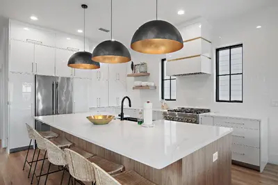 a kitchen with a large white counter and some lights at LegaSea on 30A in Inlet Beach