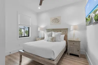 a white bedroom with a bed and a window at LegaSea on 30A in Inlet Beach