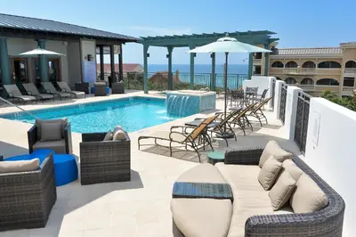 a swimming pool with wicker furniture next to a patio at WaterHouse 304- Open Air in Inlet Beach