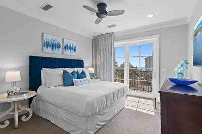 a bedroom with a bed with a blue headboard and a window at WaterHouse 304- Open Air in Inlet Beach