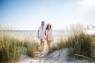 a man and woman walking through the sand at the beach at WaterHouse 304- Open Air in Inlet Beach