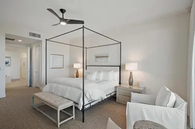 a bedroom with a canopy bed and a chair at Beach Haven in Inlet Beach