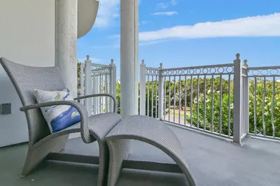 a wicker chair sitting on a porch with a fence at Beach Haven in Inlet Beach