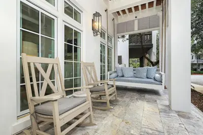a porch with two rocking chairs and a couch at Harp's Haven Main House in Inlet Beach