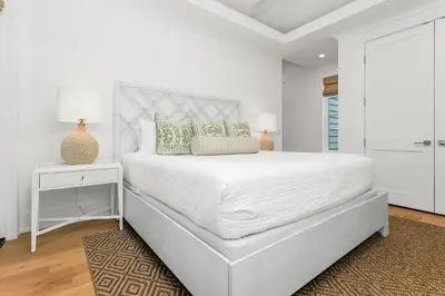 a white bedroom with a large white bed and a table at Harp's Haven Main House in Inlet Beach