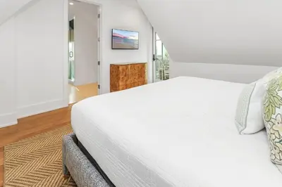 a bedroom with a white bed and a tv on the wall at Harp's Haven Main House in Inlet Beach