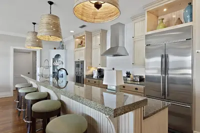 a kitchen with a stainless steel refrigerator and bar with stools at WaterHouse 402 in Inlet Beach