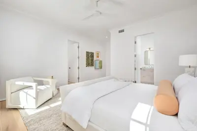 a white bedroom with a large white bed and a chair at 74 Elysee Court in Inlet Beach