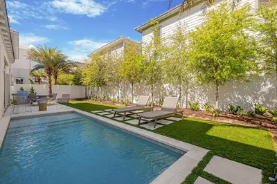 a swimming pool in a yard with two chairs next to a house at 74 Elysee Court in Inlet Beach