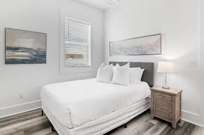 a white bedroom with a bed and a nightstand at Vitamin Sea of Seagrove in Santa Rosa Beach
