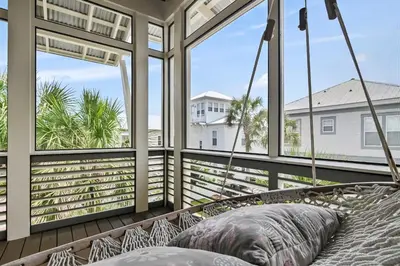 a porch with a hammock in front of windows at Southern Coastal in Inlet Beach