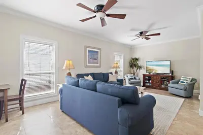 a living room with a blue couch and a ceiling fan at Fintastic in Santa Rosa Beach
