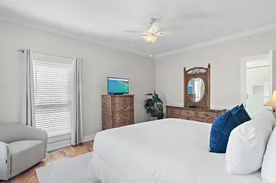 a white bedroom with a bed and a chair at Fintastic in Santa Rosa Beach
