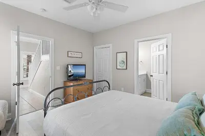 a white bedroom with a bed and a television at Emerald Escape in Santa Rosa Beach