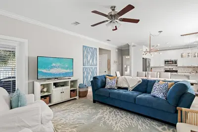 a living room with a blue couch and a tv at Emerald Escape in Santa Rosa Beach