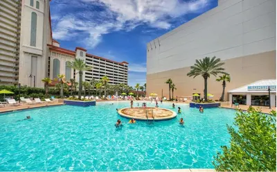a pool at a resort with people in the water at Spacious 1-Bedroom! Ocean Views & 5 Pools Resort! by Dolce Vita Getaways PCB in Panama City Beach