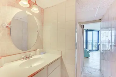 a bathroom with a sink and a mirror and a shower at Gulf-View Balcony Beachfront Condo in PCB! in Panama City Beach