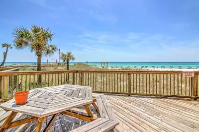 a wooden deck with a table and a chair on the beach at Gulf-View Balcony Beachfront Condo in PCB! in Panama City Beach