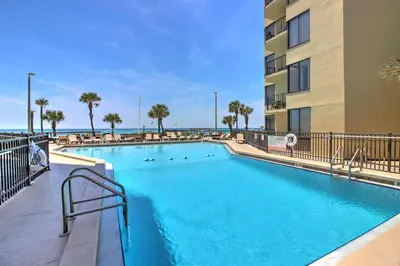 a swimming pool at a resort with palm trees and a building at Gulf-View Balcony Beachfront Condo in PCB! in Panama City Beach