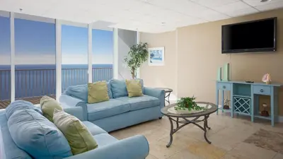 a living room with a blue couch and a tv at Tidewater Escape: 1BR/2BA beachfront condo, sleeps 6, Gulf views & comfort! in Panama City Beach