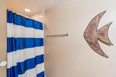 a bathroom with a shower curtain and a starfish on the wall at Shores of Panama 2325 condo in Panama City Beach