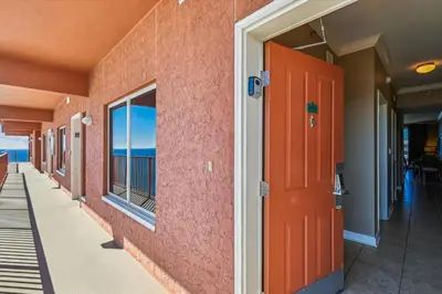 a corridor of a building with a red door at Shores of Panama 2325 condo in Panama City Beach