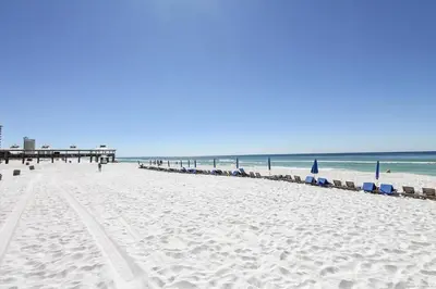 a beach with chairs and a pier and the ocean at Shores of Panama 2325 condo in Panama City Beach