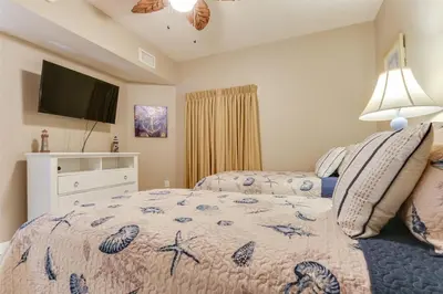 a bedroom with a bed and a flat screen tv at Shores of Panama 1601 condo in Panama City Beach