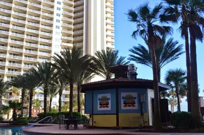 a small building in front of a building with palm trees at Shores of Panama 1601 condo in Panama City Beach