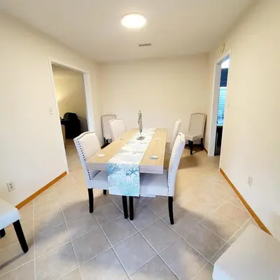 a dining room with a table and white chairs at Spacious 3BR Family Beach Home 5 Mins to Panama City Beach & Sleeps 9 Hot tub in Panama City Beach