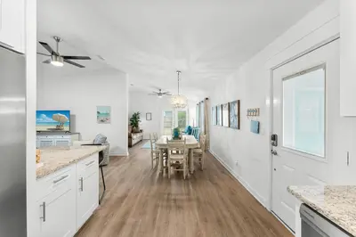 a kitchen and dining room with white cabinets and a table at Aqua Believe It in Panama City Beach