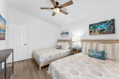 a bedroom with two beds and a ceiling fan at Aqua Believe It in Panama City Beach